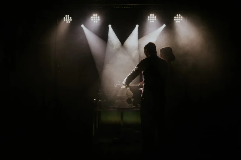 Para krojąca tort weselny, reflektory na scenie.