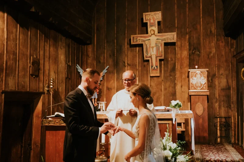 Ślub w drewnianym kościele, para wymienia obrączki.