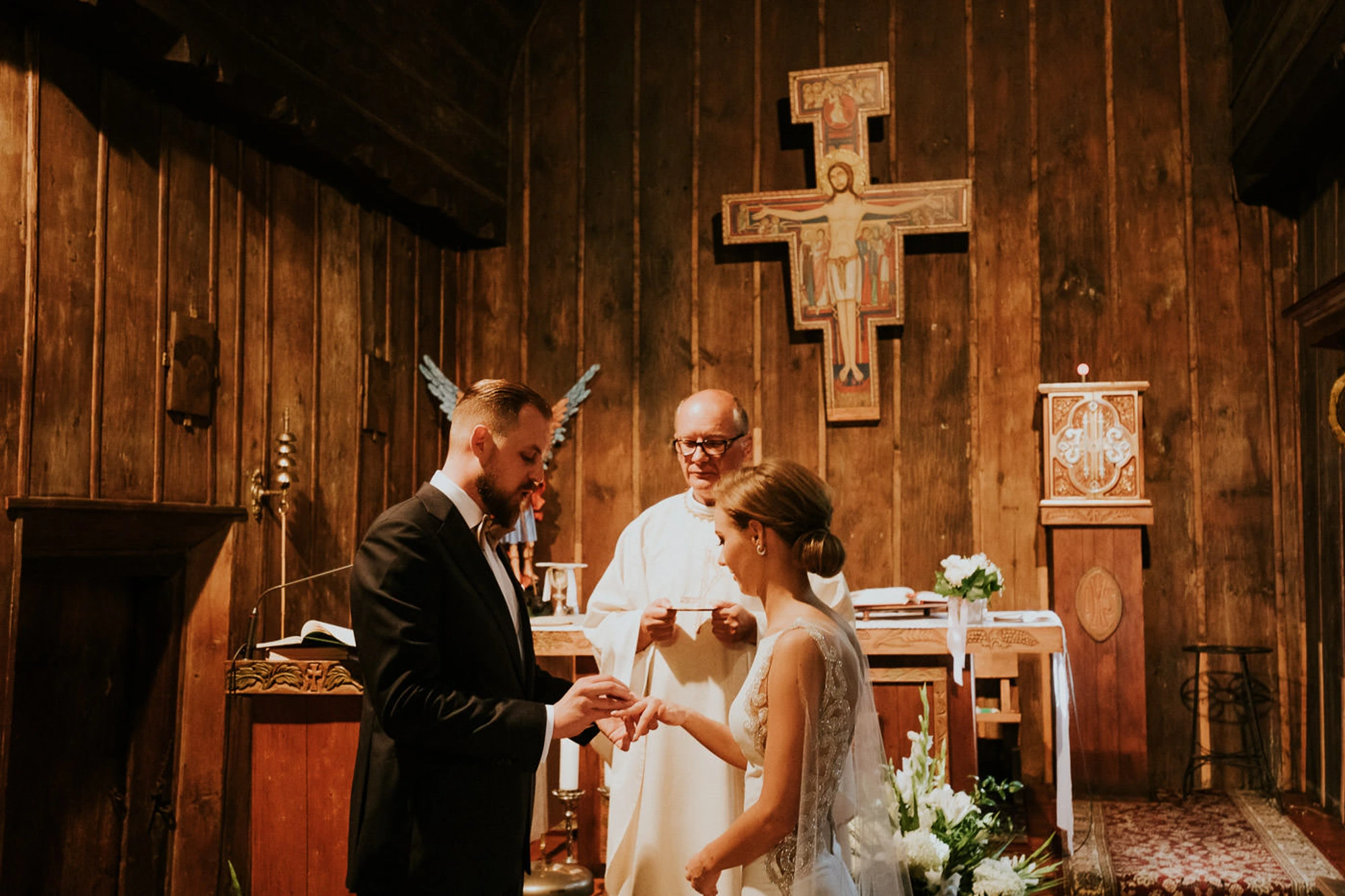 Ślub w drewnianym kościele, para wymienia obrączki.
