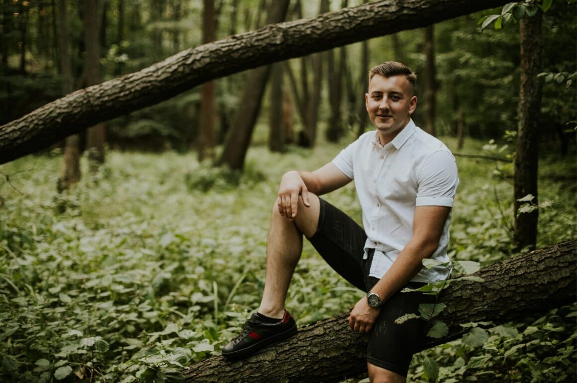 Mężczyzna w lesie siedzi na pniu drzewa