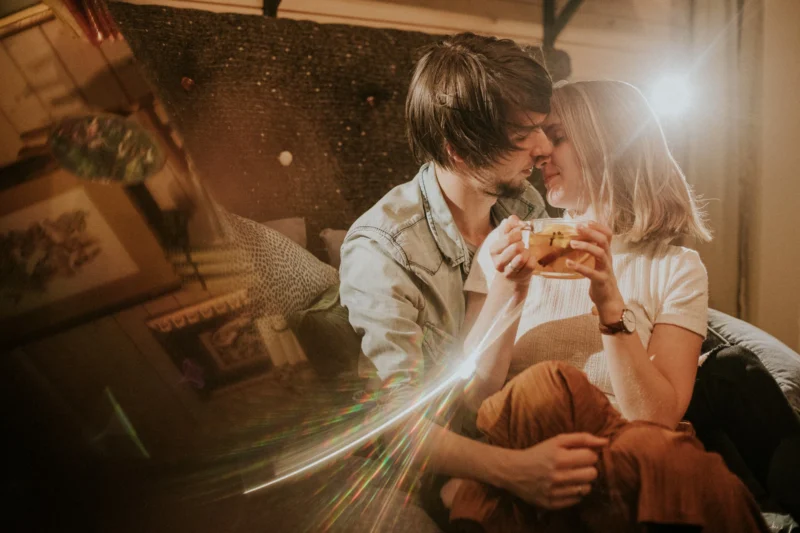 Para przytulająca się na kanapie z filiżanką herbaty