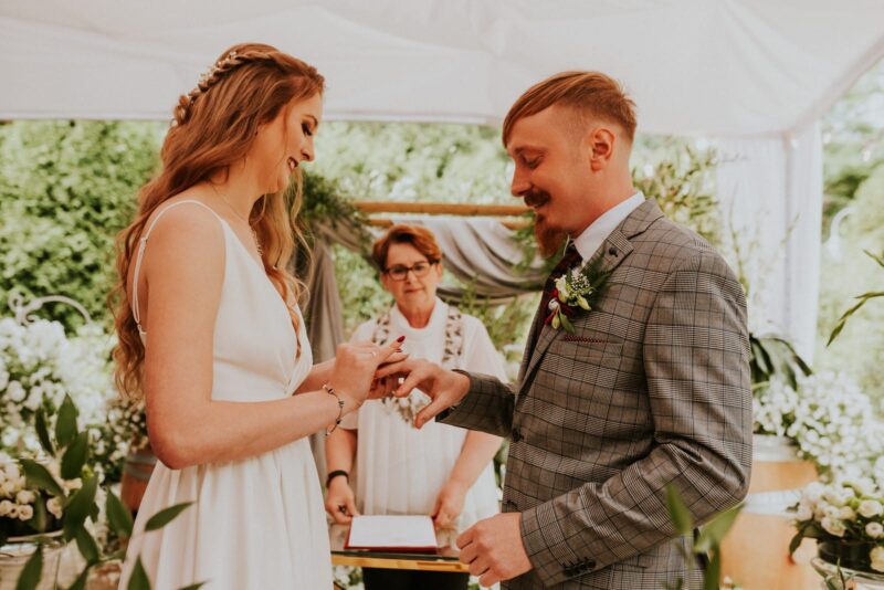 Para młoda wymienia obrączki na ślubie w plenerze.