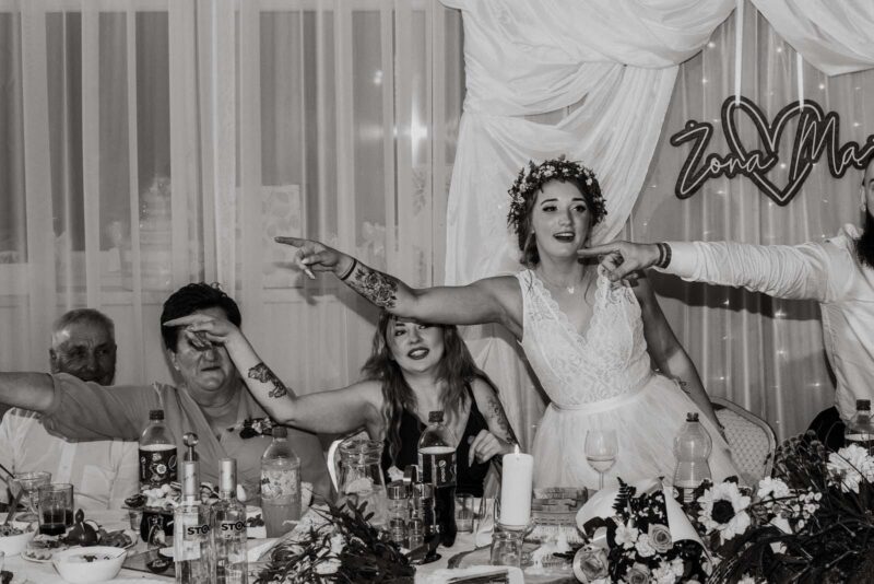 Goście weselni w zabawie przy stole.