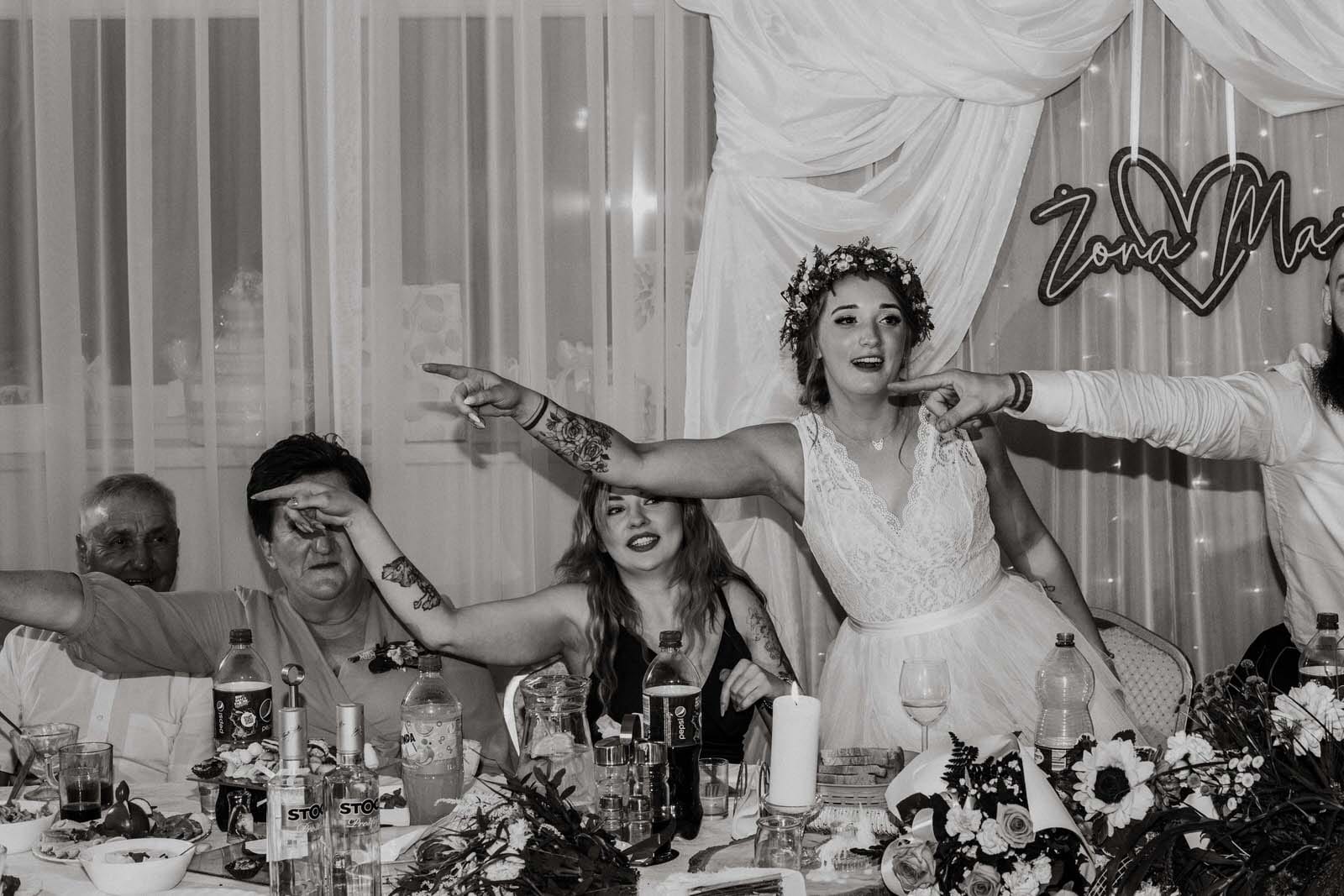 Goście weselni w zabawie przy stole.