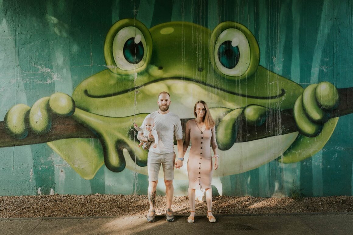 Rodzina przed graffiti z żabą na ścianie.