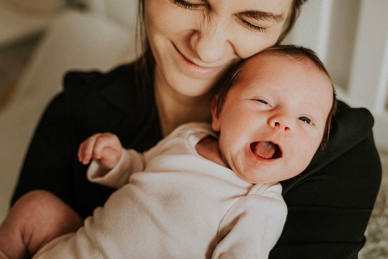 Szczęśliwa matka trzyma uśmiechnięte niemowlę