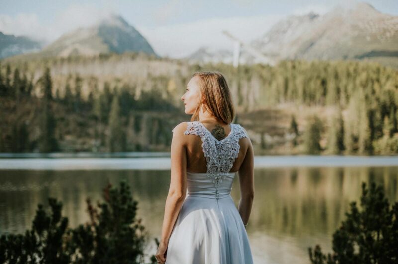 Kobieta w białej sukni na tle jeziora i gór.