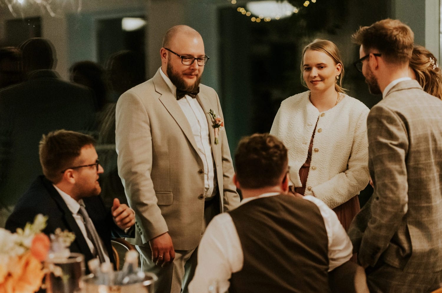 Grupa osób rozmawia przy stole podczas przyjęcia.