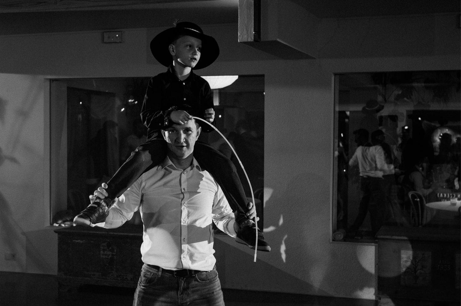 Dziecko na ramionach mężczyzny w kapeluszu.