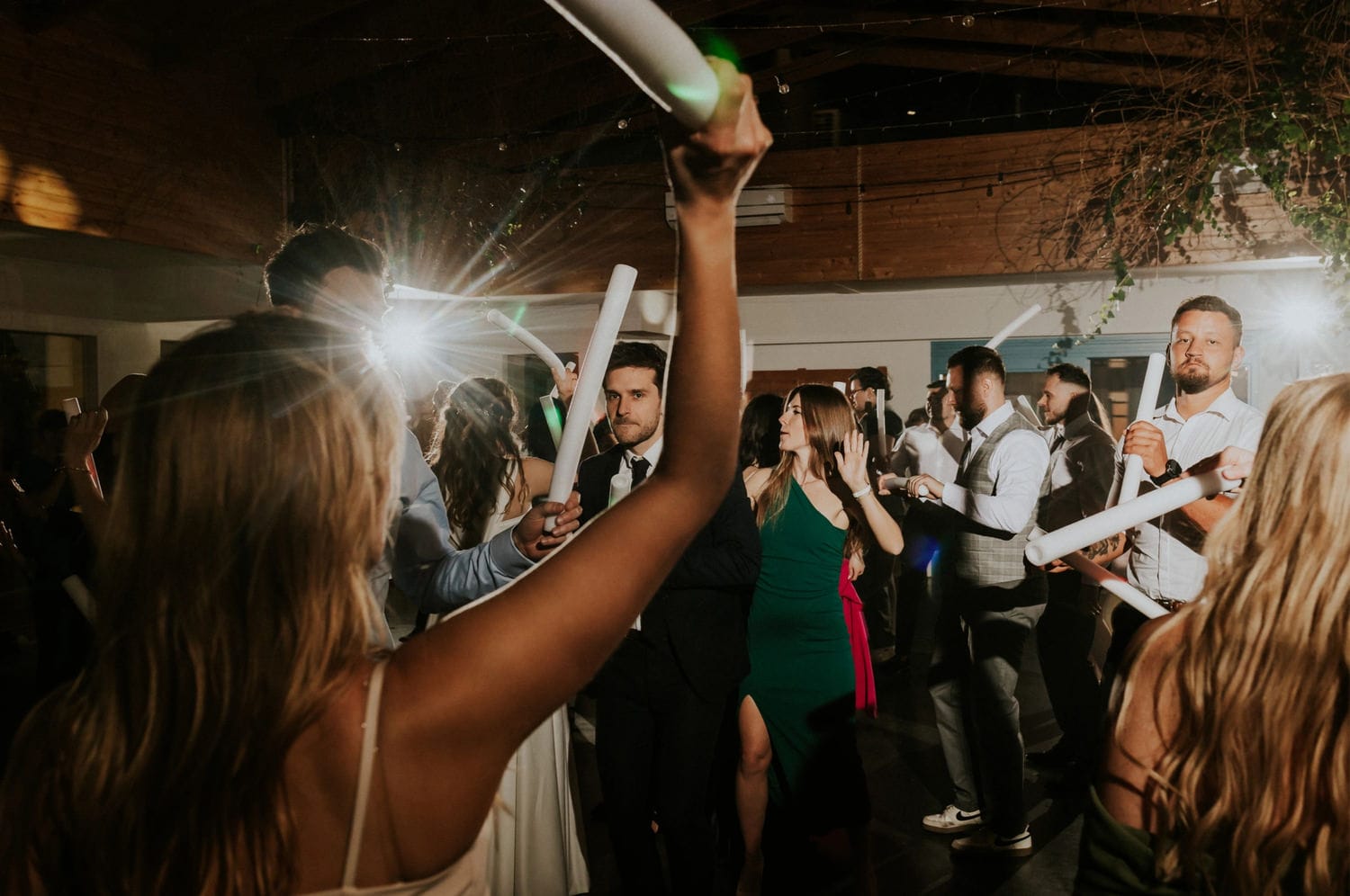 Osoby tańczące na weselu z rurkami LED.