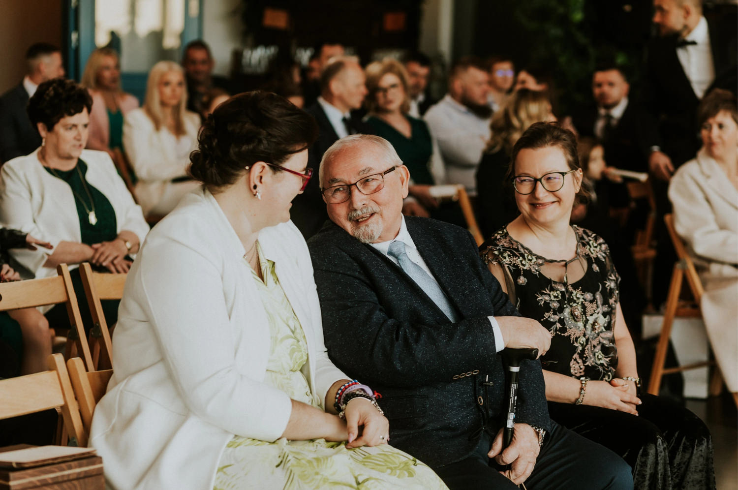 Uśmiechnięci ludzie siedzący na krzesłach podczas wydarzenia.