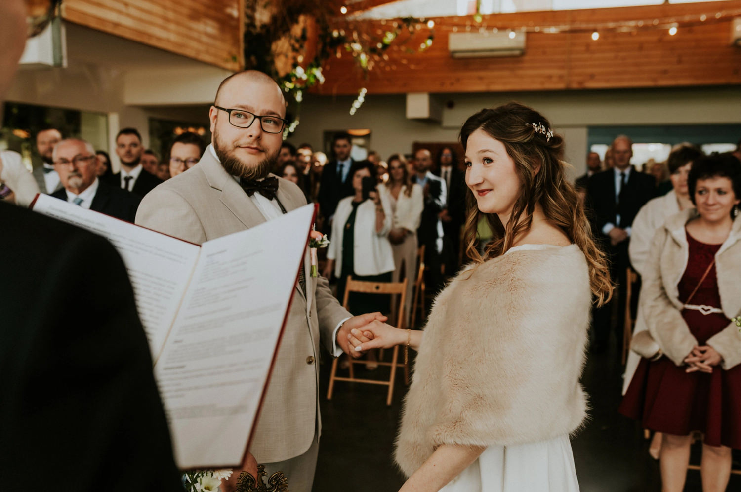 Para młoda na ślubie z gośćmi w tle.