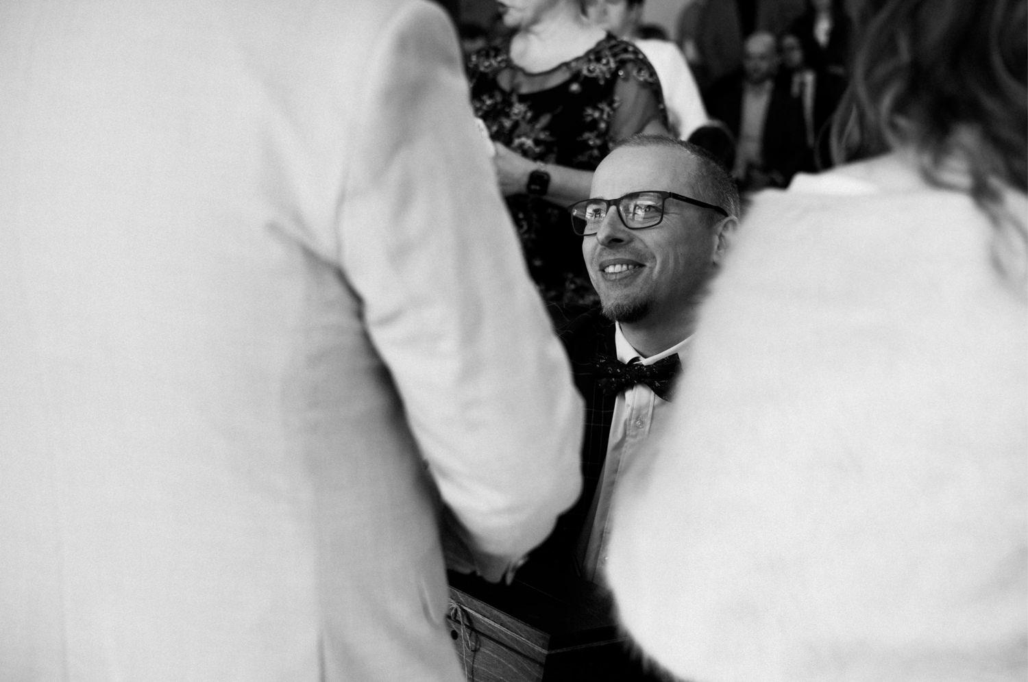 Uśmiechnięty mężczyzna w okularach na weselu.