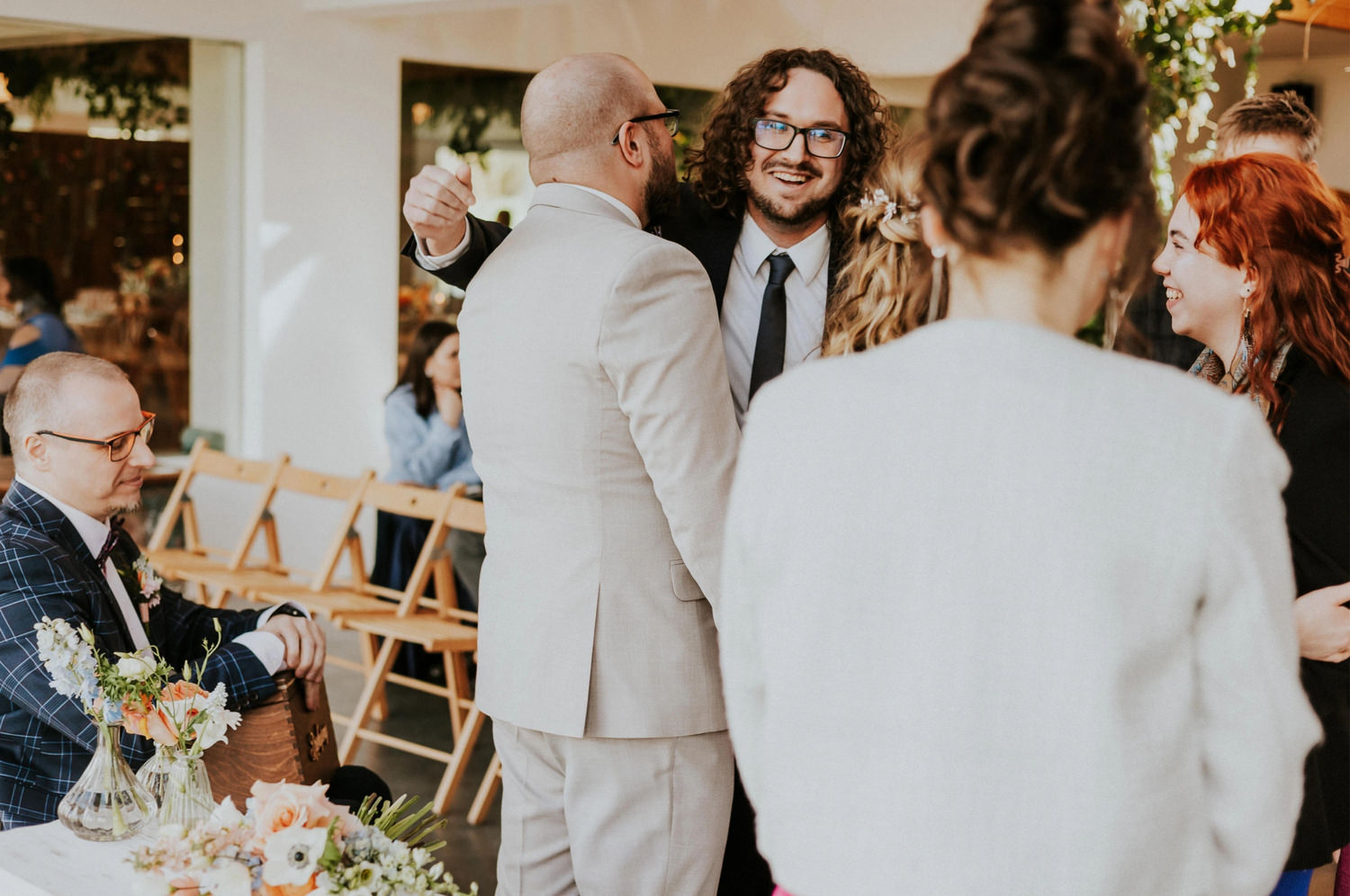 Ludzie świętujący w eleganckim wnętrzu z kwiatami.
