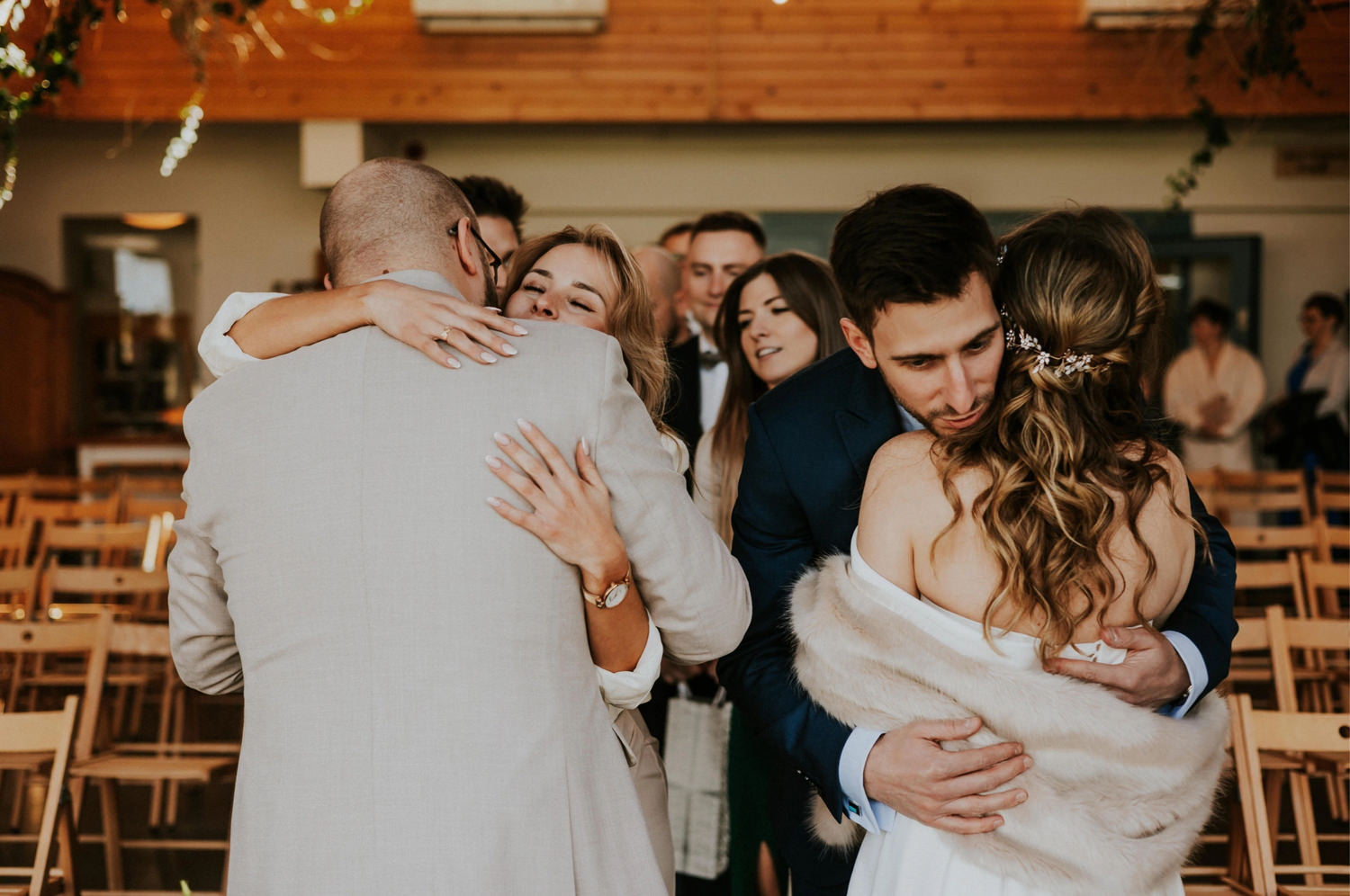 Ludzie przytulają się na weselu, radosna atmosfera.