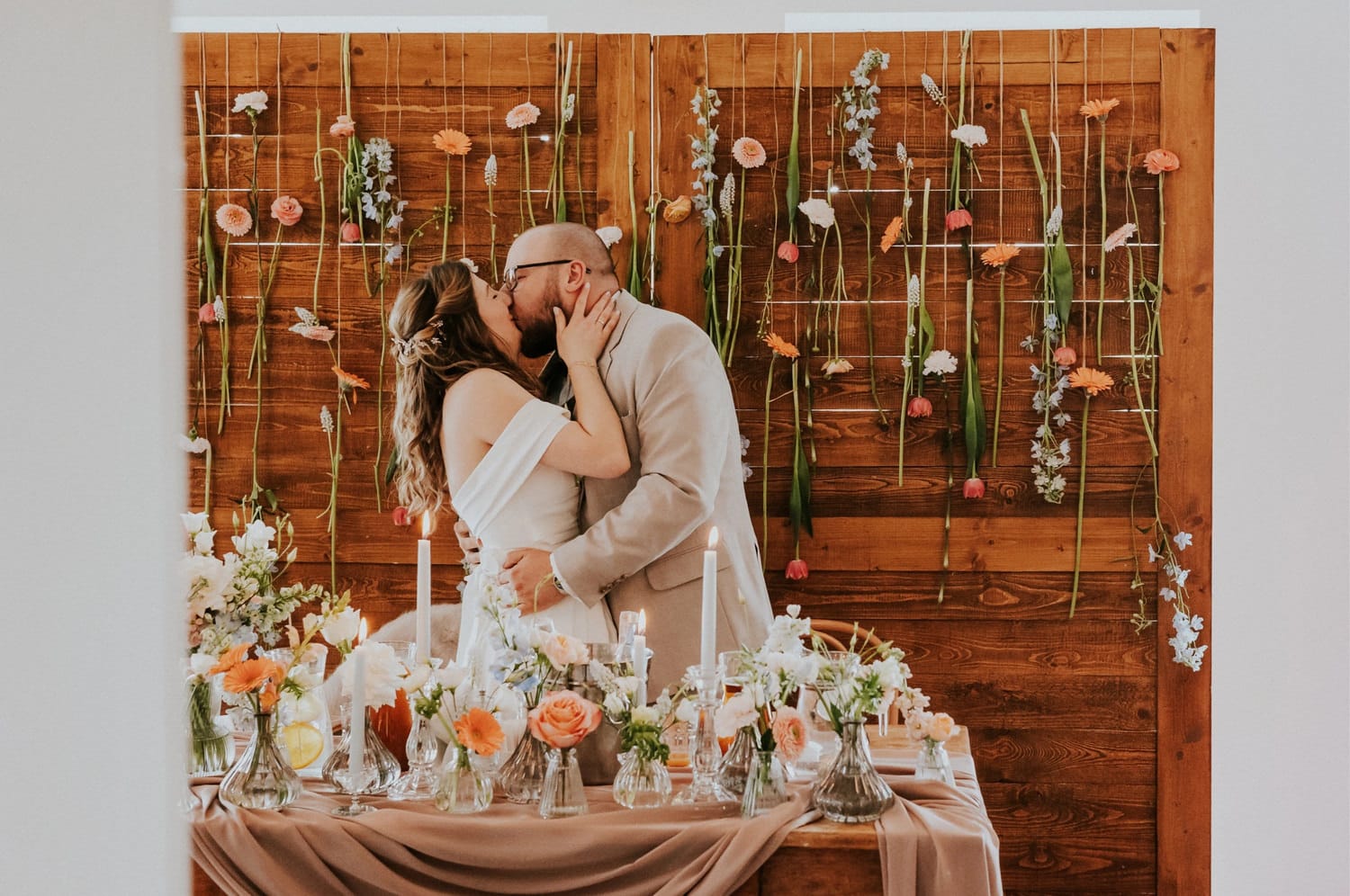 Para młoda całuje się przy rustykalnym ołtarzu ślubnym.