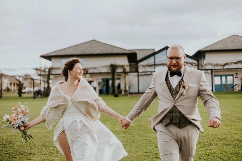 Para młoda biegnie przez zieloną trawę.