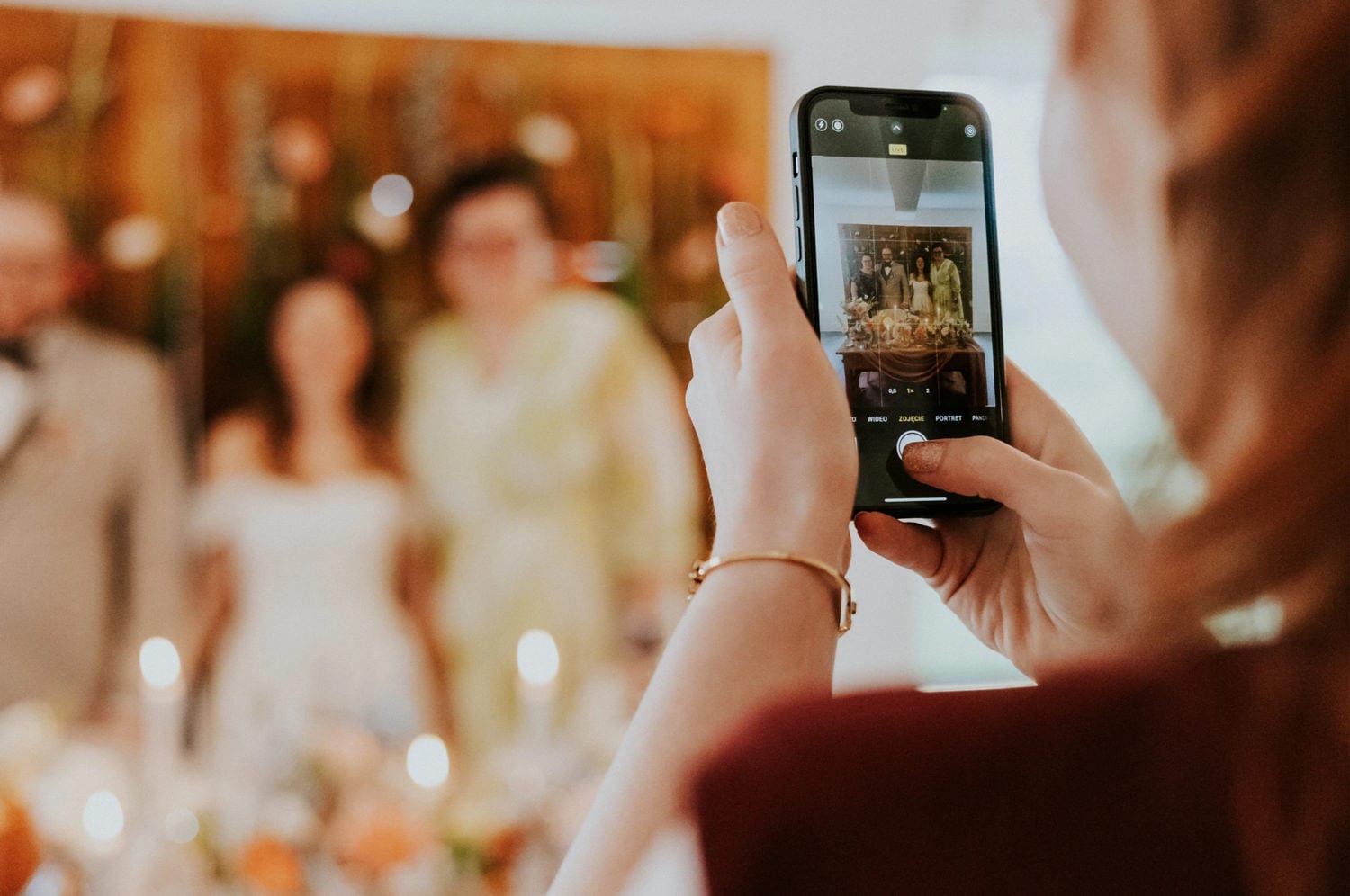 Osoba robi zdjęcie grupowe telefonem na weselu.