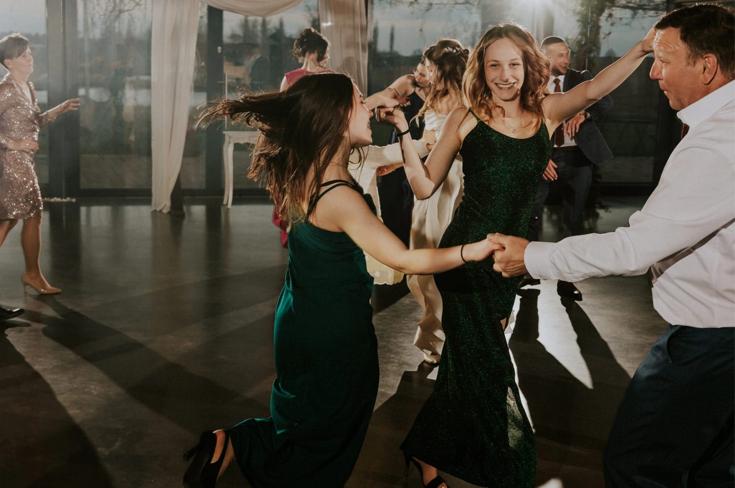 Grupa ludzi tańczy na weselu, śmiech i zabawa