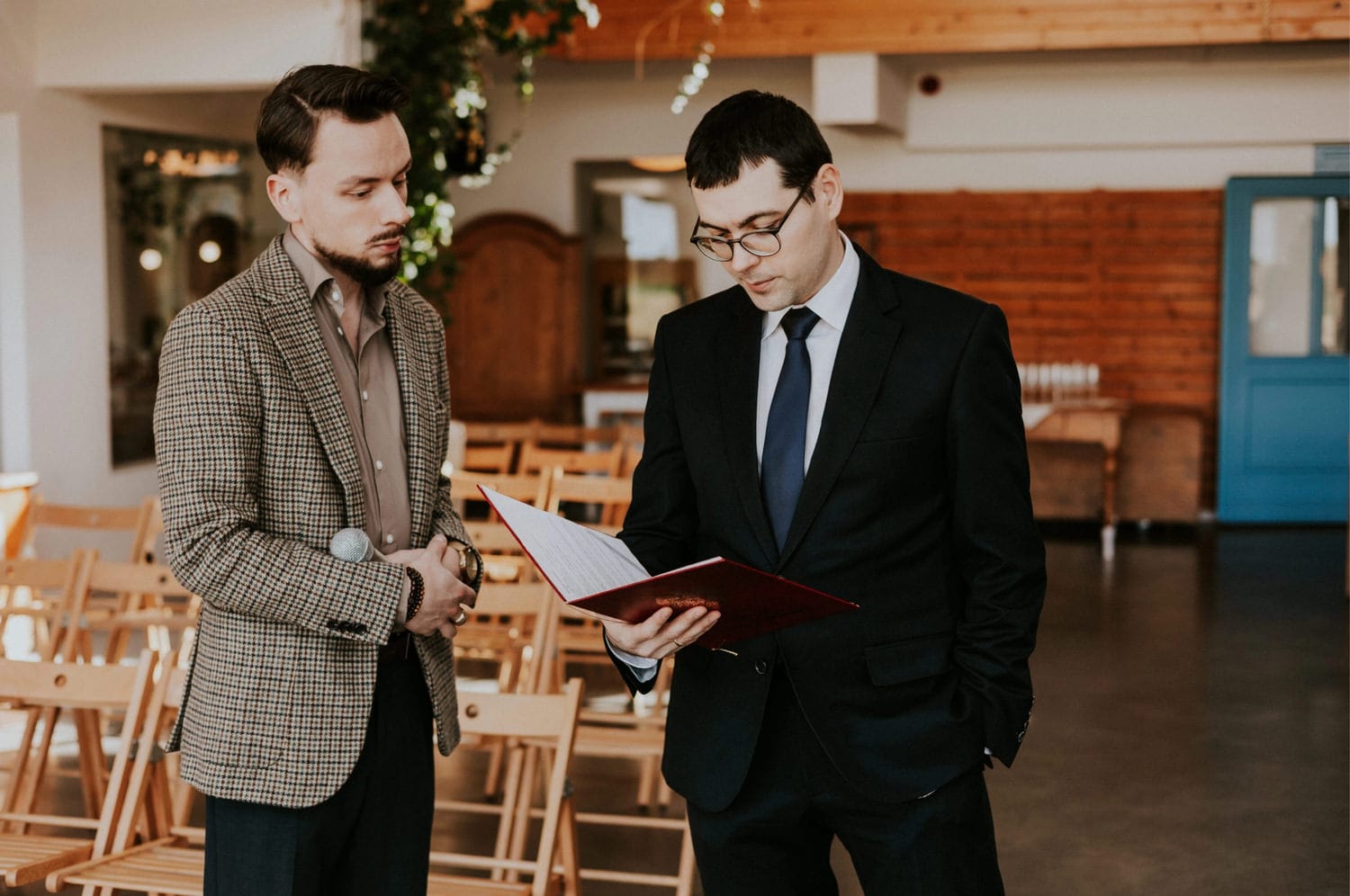 Dwóch mężczyzn omawia dokument w sali konferencyjnej.