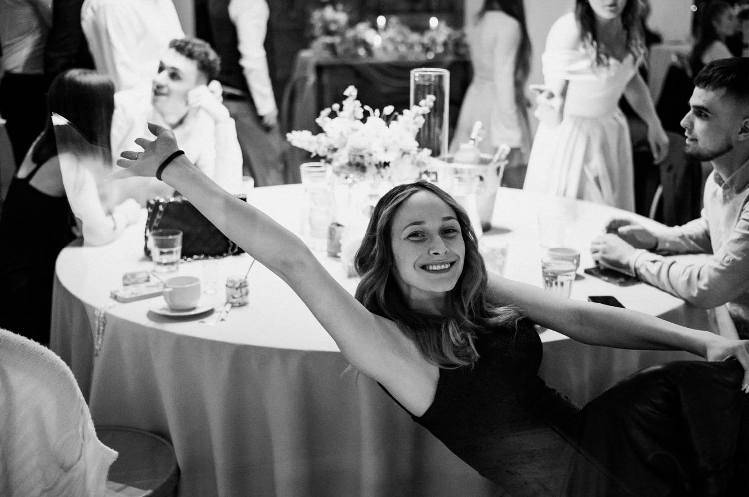 Uśmiechnięta kobieta na przyjęciu weselnym przy stole.