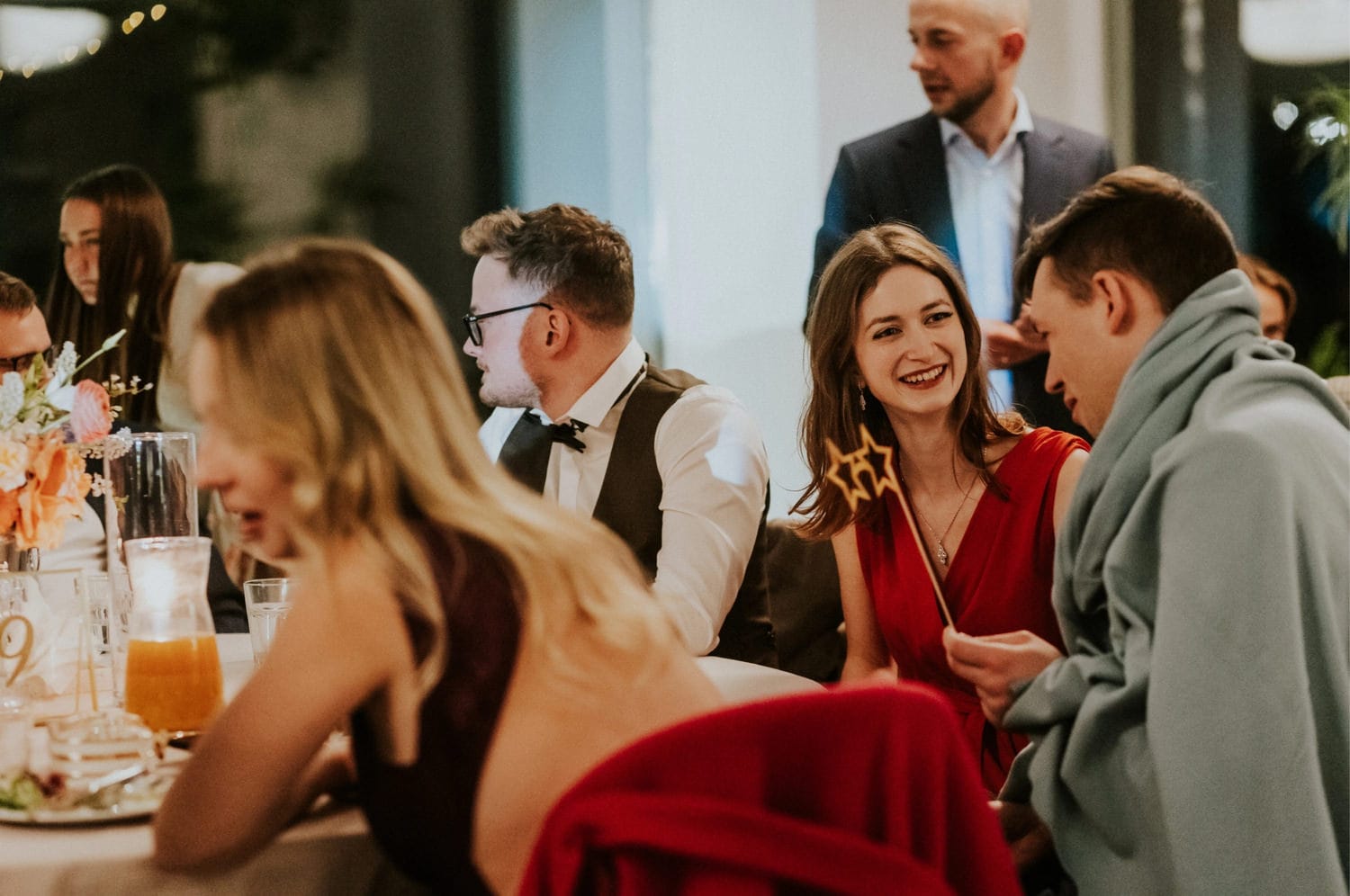 Goście rozmawiający przy stole na przyjęciu weselnym.