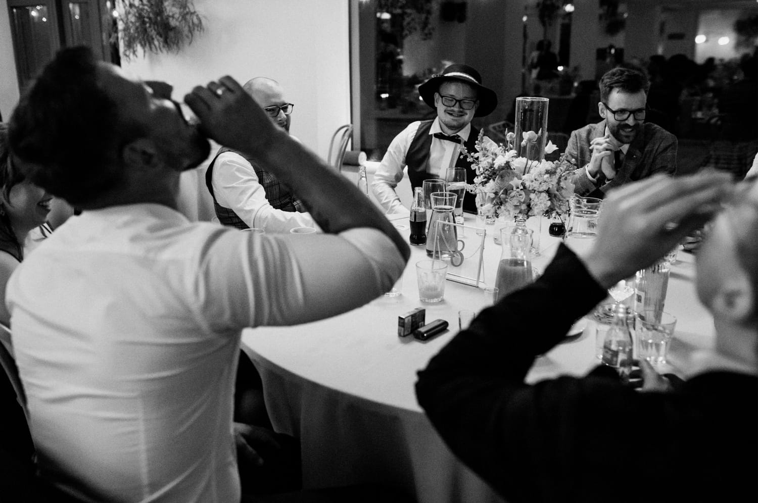 Grupa ludzi świętuje przy stole weselnym.