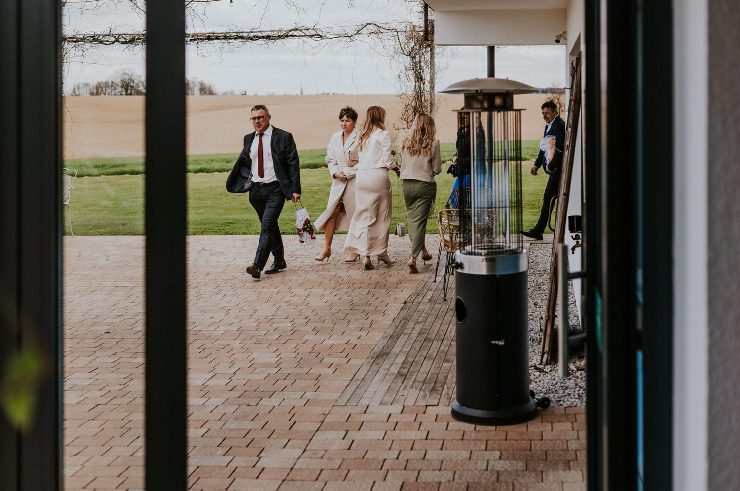 Grupa ludzi spacerująca po tarasie przy domu.