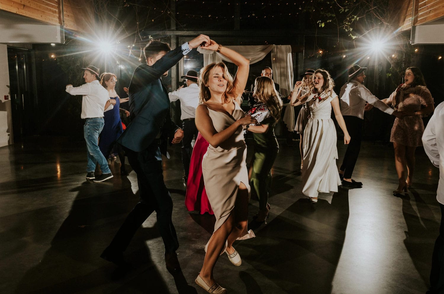 Grupa ludzi tańczy na przyjęciu weselnym.