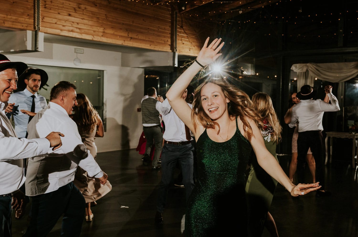 Osoby tańczące na weselu, radosna atmosfera.