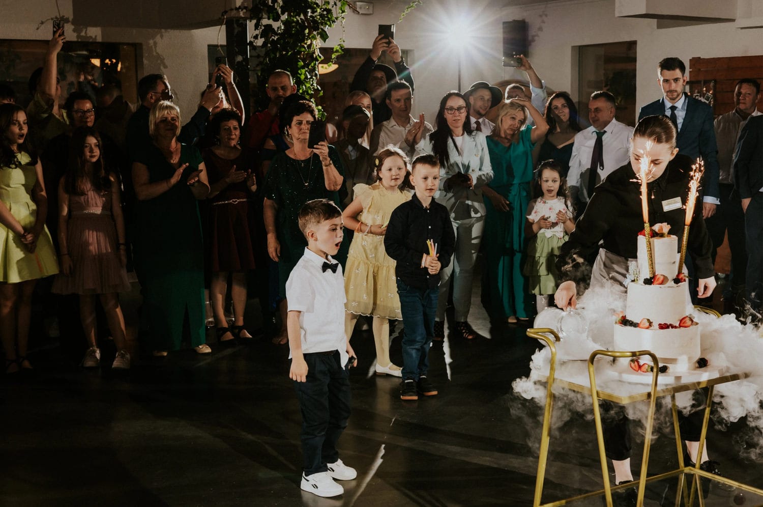 Tłum obserwuje tort z fontannami na przyjęciu.