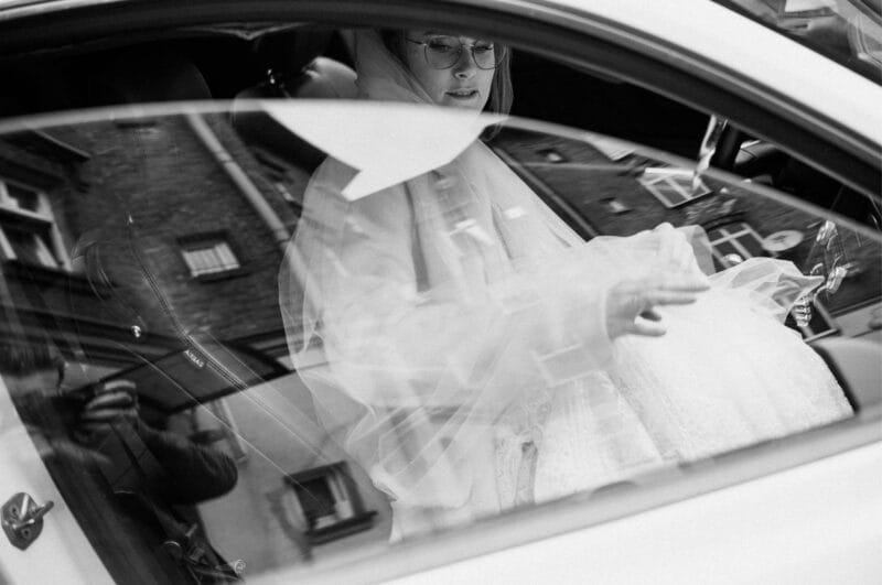 Panna młoda w samochodzie, widziana przez szybę.