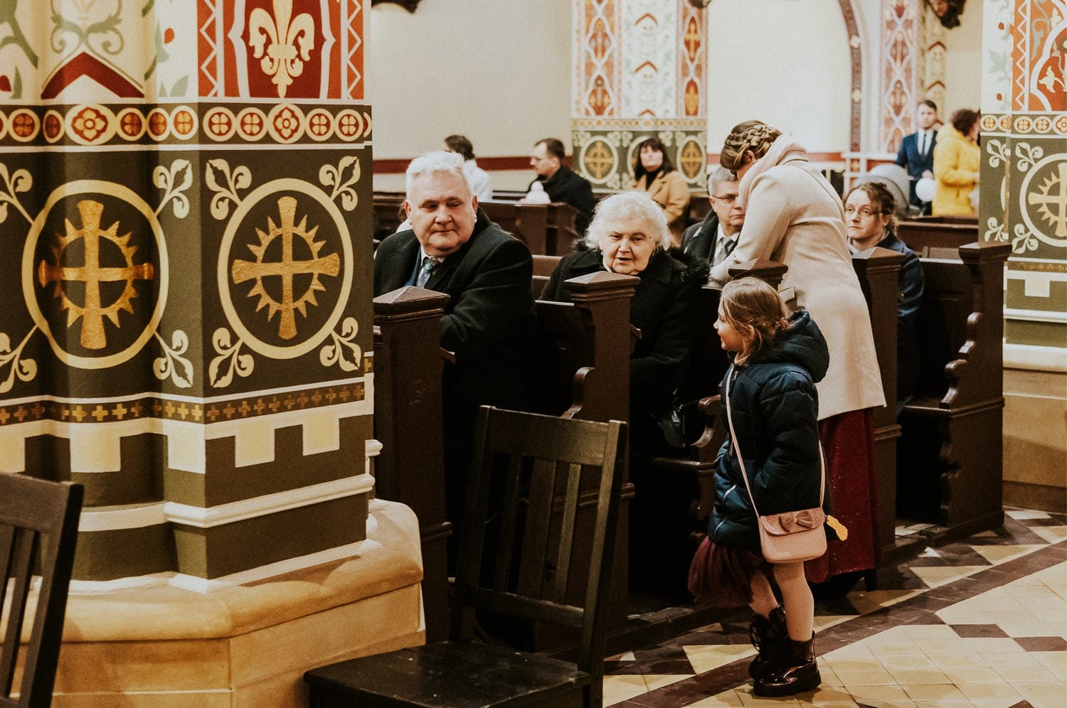 Ludzie w kościele, ozdobne kolumny, dziecko rozmawia.