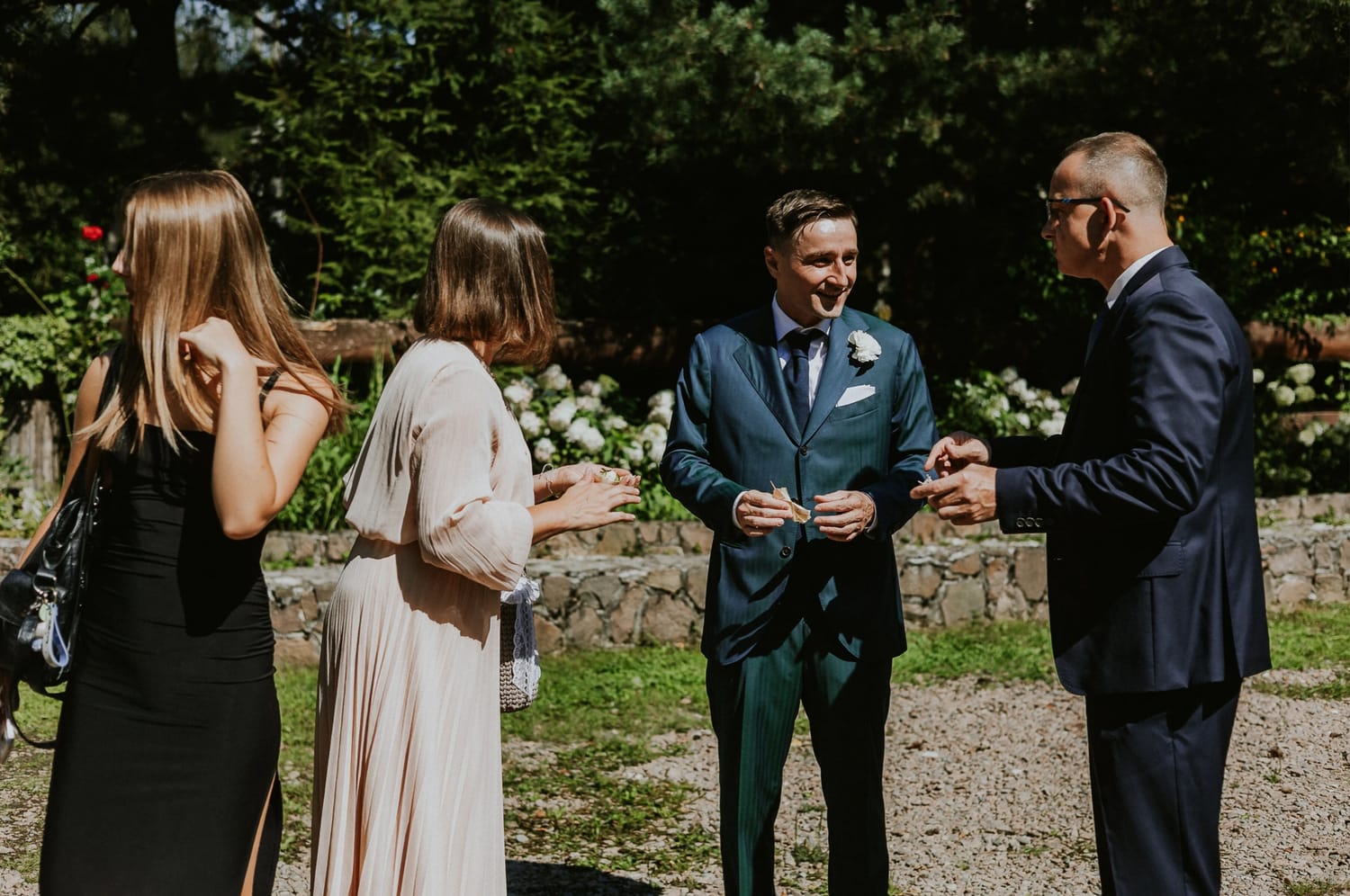 Ludzie rozmawiają na świeżym powietrzu, elegancko ubrani.