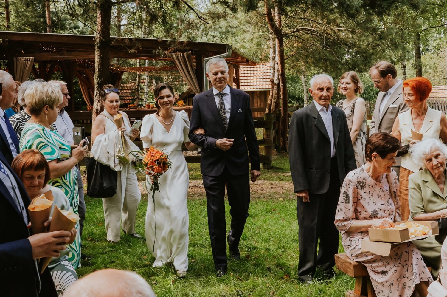 Para młoda z gośćmi na weselu na świeżym powietrzu.