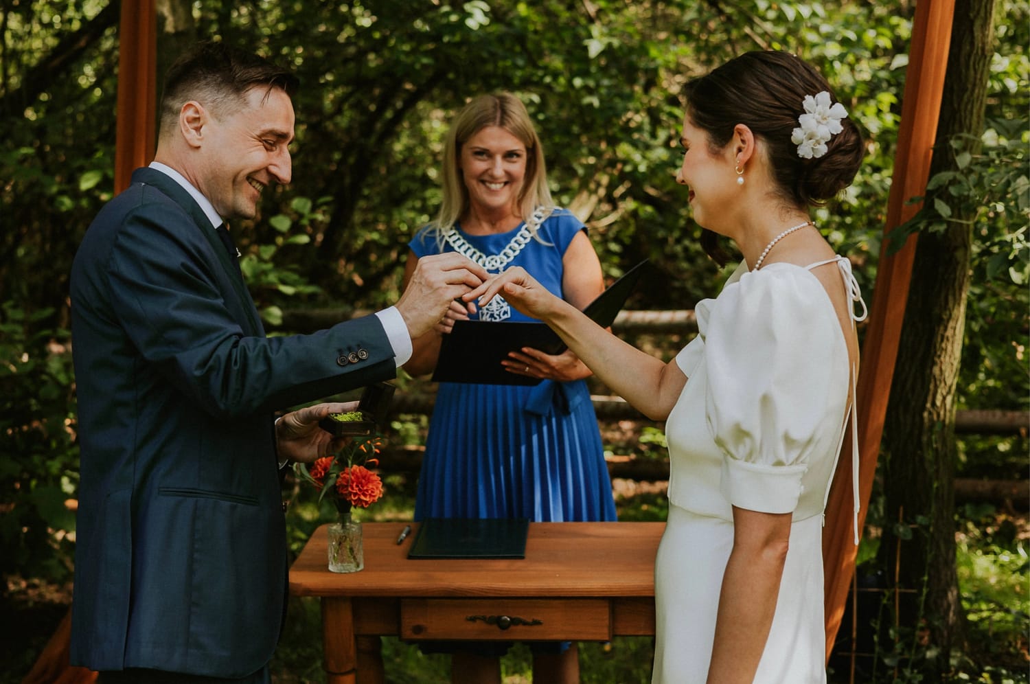 Para wymienia obrączki podczas ceremonii ślubnej w plenerze.