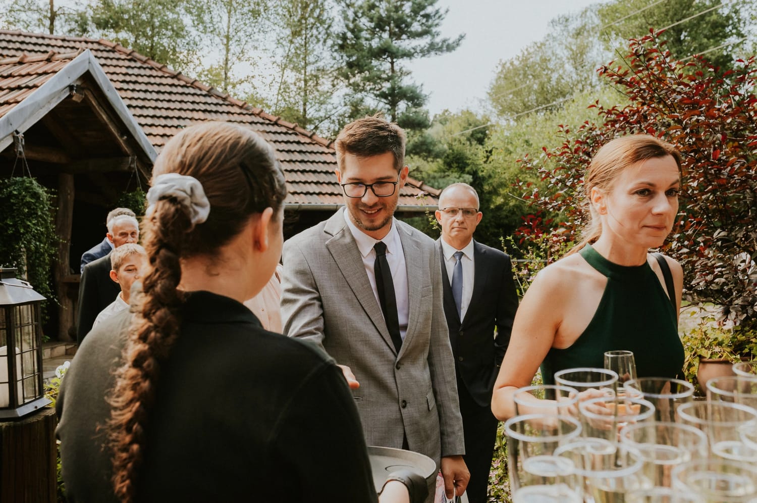 Goście w eleganckich strojach na przyjęciu plenerowym.