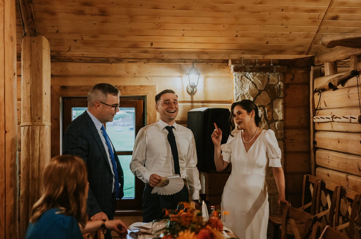 Ludzie rozmawiający w drewnianym wnętrzu.