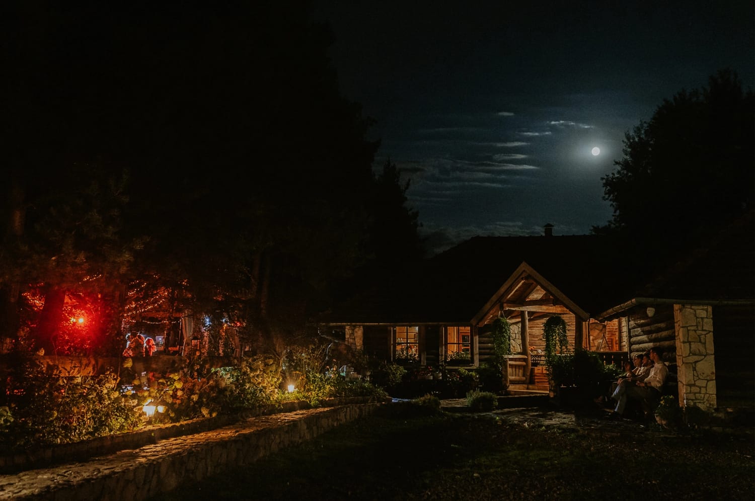 Drewniany dom nocą, światło księżyca i lampy.